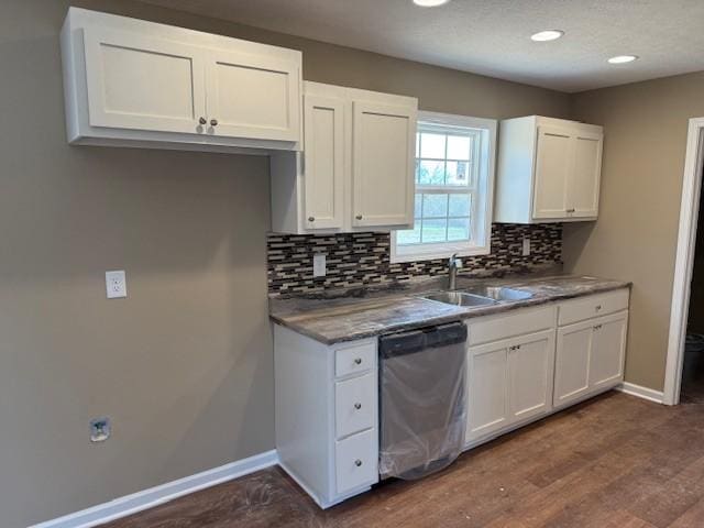 kitchen featuring dark wood-type flooring, sink, stainless steel dishwasher, decorative backsplash, and white cabinetry