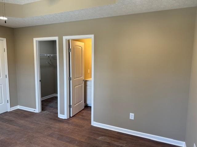 unfurnished bedroom with dark hardwood / wood-style flooring, a textured ceiling, and a closet