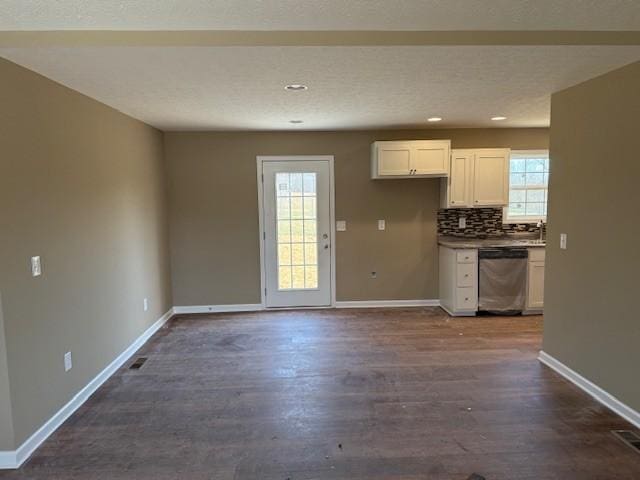 kitchen with dark hardwood / wood-style flooring, backsplash, white cabinetry, and stainless steel dishwasher