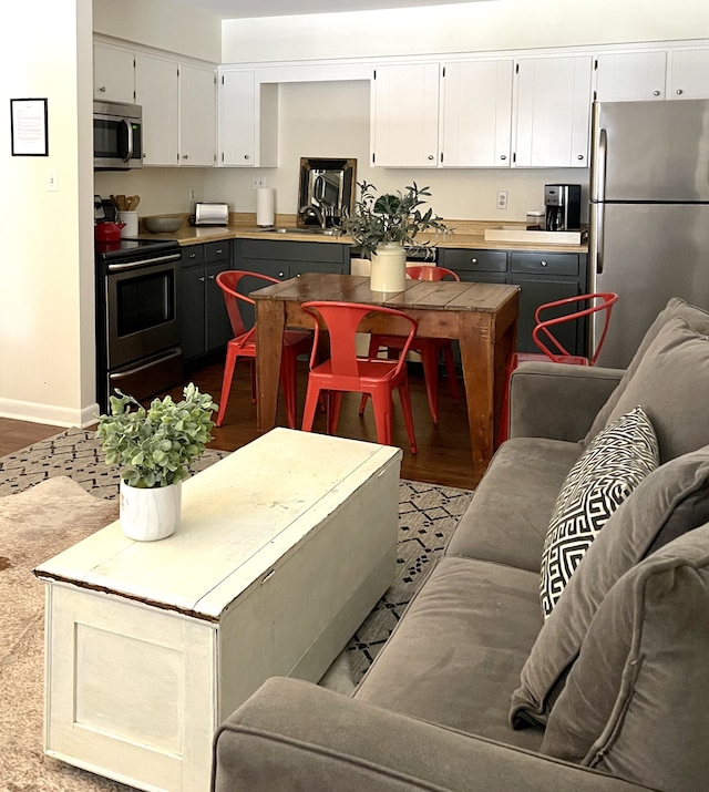 kitchen with gray cabinetry, sink, stainless steel appliances, hardwood / wood-style floors, and white cabinets