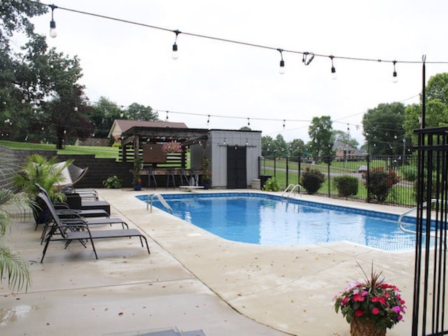 view of swimming pool featuring a patio and an outbuilding