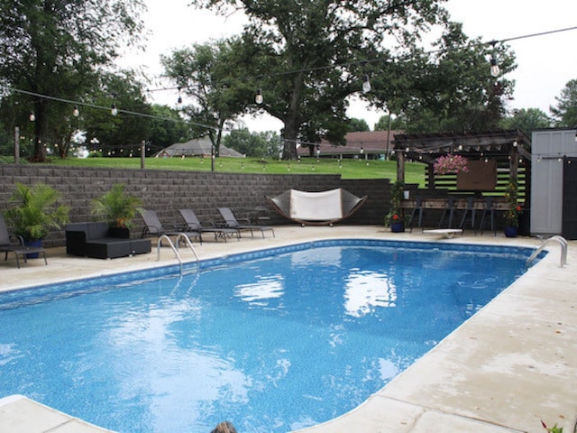 view of swimming pool with outdoor lounge area, a diving board, a pergola, and a patio