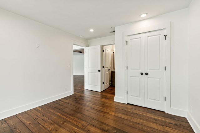 unfurnished bedroom featuring dark wood-type flooring and a closet