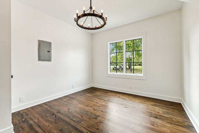 spare room with electric panel, dark hardwood / wood-style floors, and an inviting chandelier