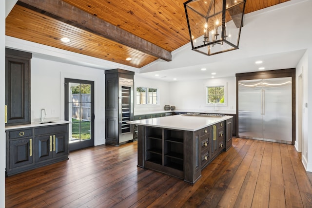 kitchen with a center island, lofted ceiling with beams, hanging light fixtures, dark hardwood / wood-style flooring, and stainless steel appliances