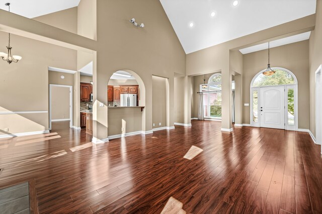 entryway with a healthy amount of sunlight, dark hardwood / wood-style floors, and high vaulted ceiling