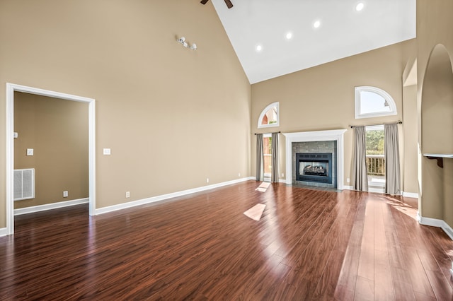 unfurnished living room featuring dark hardwood / wood-style floors, high vaulted ceiling, and a tile fireplace