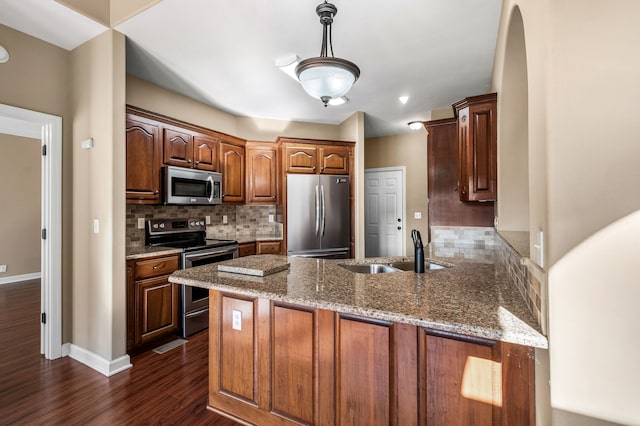 kitchen with dark wood-type flooring, sink, kitchen peninsula, stainless steel appliances, and backsplash