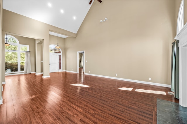 unfurnished living room featuring ceiling fan, dark wood-type flooring, and high vaulted ceiling