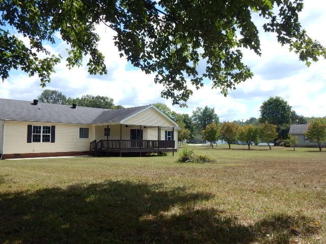 rear view of property featuring a wooden deck and a yard