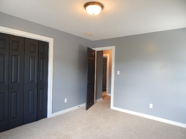 unfurnished bedroom with light carpet and a closet