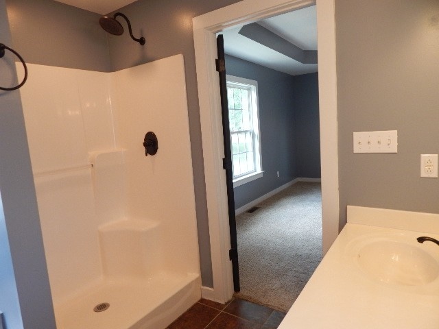 bathroom with walk in shower, vanity, and tile patterned floors