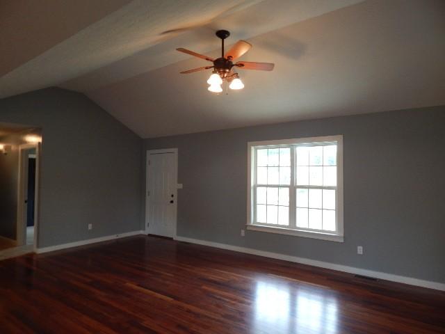 unfurnished room with ceiling fan, lofted ceiling, and dark wood-type flooring