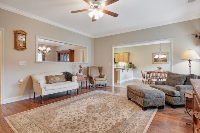 living room with ceiling fan with notable chandelier, wood-type flooring, ornamental molding, and sink