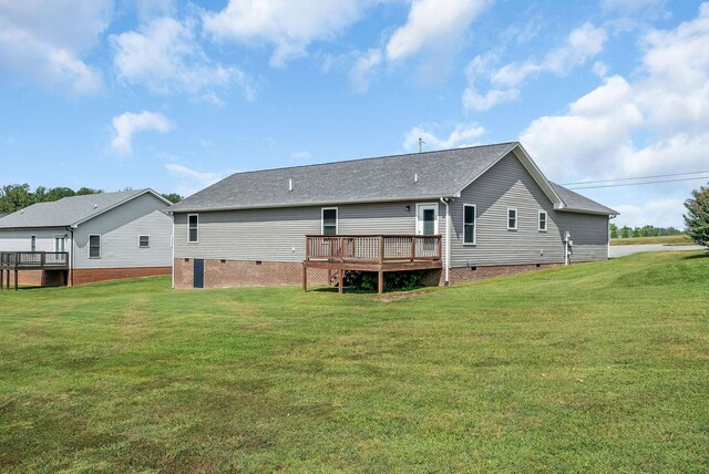 rear view of house featuring a wooden deck and a lawn