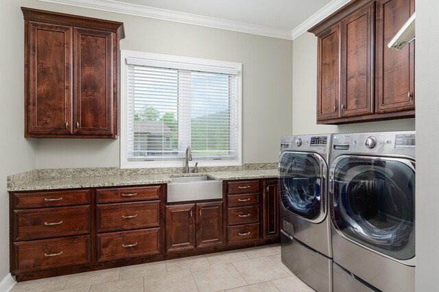 clothes washing area with cabinets, sink, light tile patterned floors, ornamental molding, and washing machine and dryer