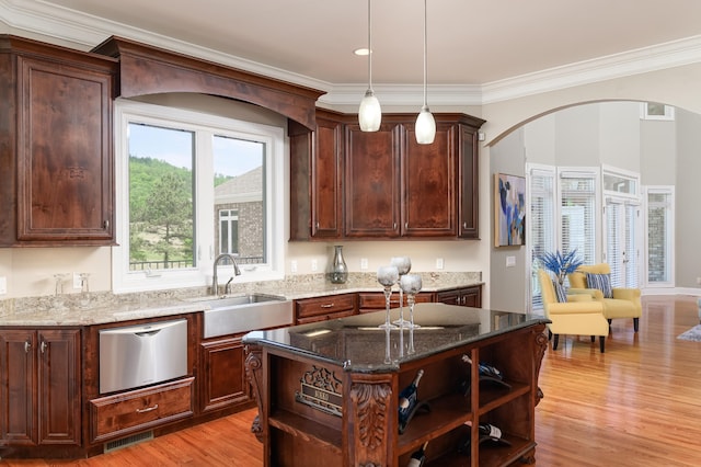 kitchen with dark stone counters, light hardwood / wood-style floors, a kitchen island, and sink