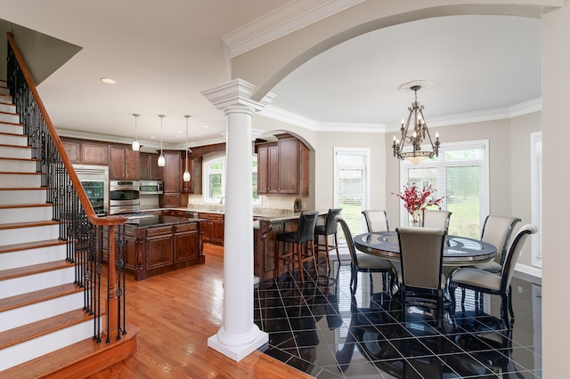 dining space featuring dark hardwood / wood-style flooring, a chandelier, crown molding, and ornate columns