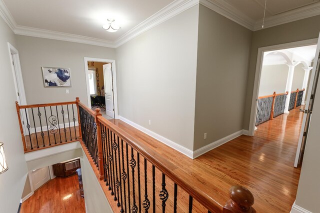 corridor with ornamental molding and hardwood / wood-style flooring