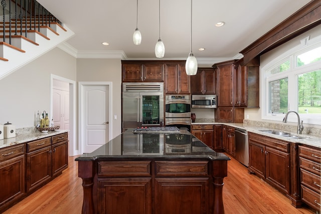 kitchen featuring stainless steel appliances, hanging light fixtures, light hardwood / wood-style floors, and a center island