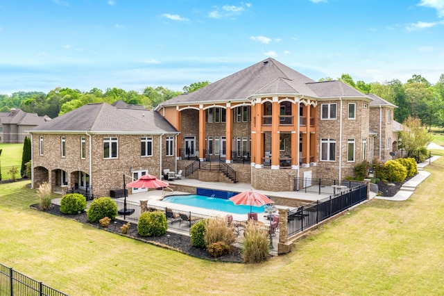 rear view of house featuring a lawn, a patio, and a fenced in pool