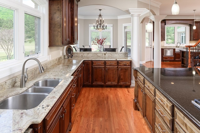 kitchen with pendant lighting, a chandelier, hardwood / wood-style flooring, sink, and decorative columns