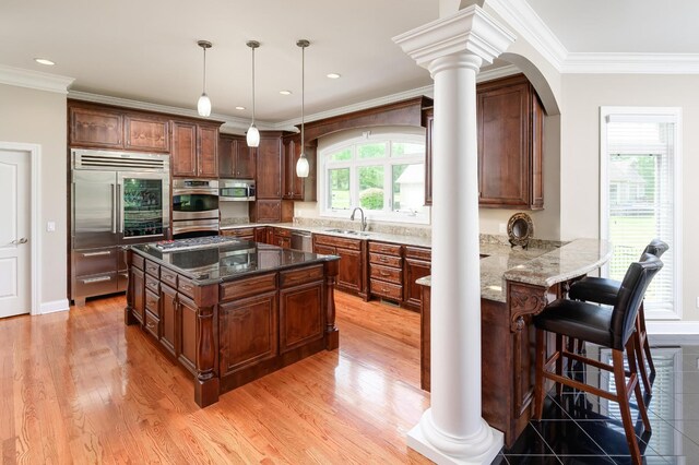 kitchen featuring pendant lighting, stainless steel appliances, decorative columns, and a kitchen island