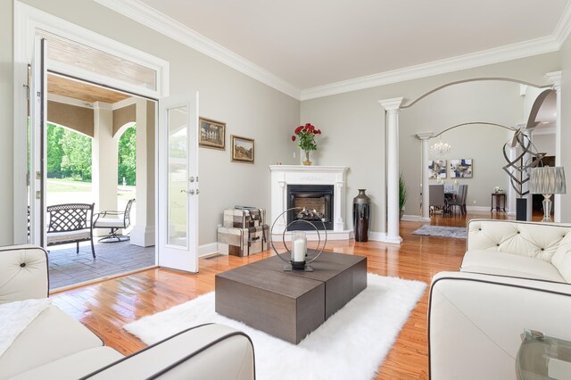 living room with light hardwood / wood-style floors, crown molding, and ornate columns