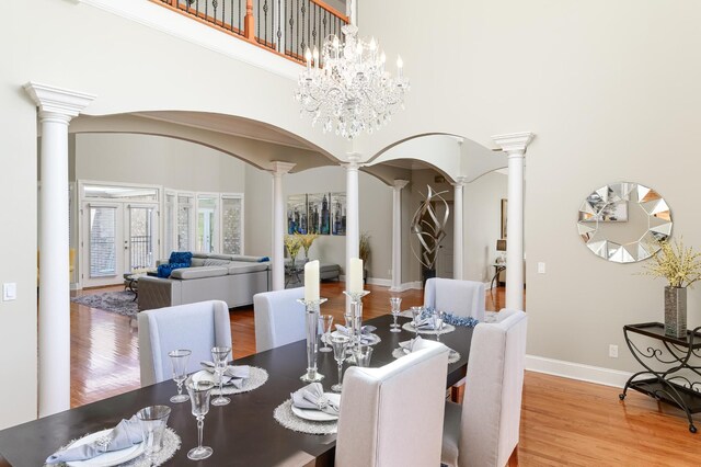 dining space featuring decorative columns, a towering ceiling, and hardwood / wood-style floors