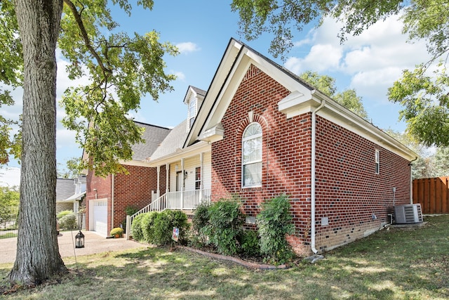 view of side of property with a yard, covered porch, central AC unit, and a garage