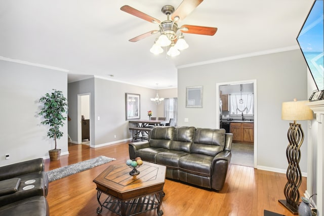 living room featuring sink, crown molding, light hardwood / wood-style flooring, and ceiling fan with notable chandelier