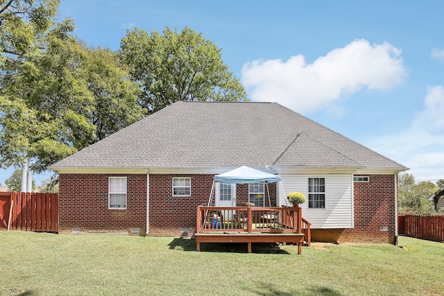 rear view of property featuring a wooden deck and a lawn