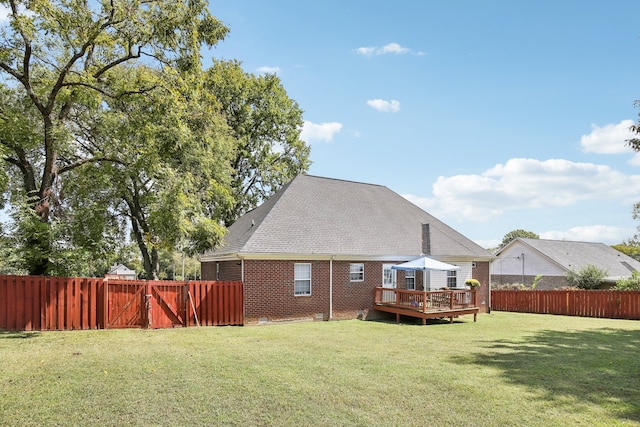 rear view of property with a wooden deck and a lawn