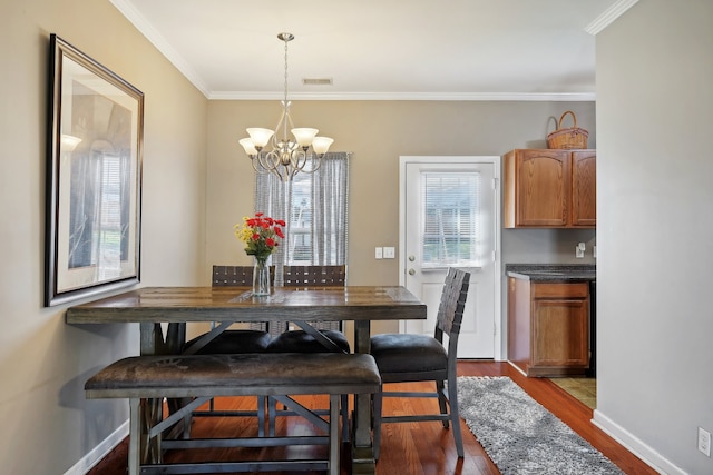 dining room with crown molding, wood-type flooring, and a chandelier