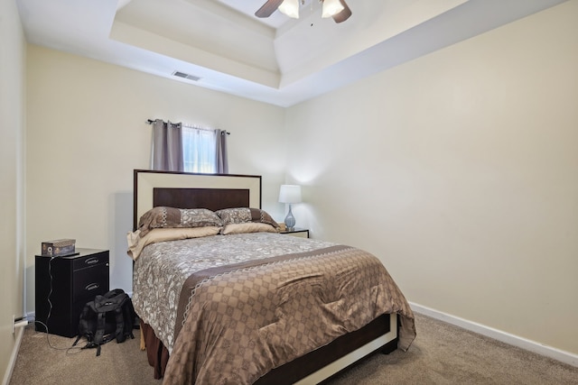 bedroom with carpet, a tray ceiling, and ceiling fan