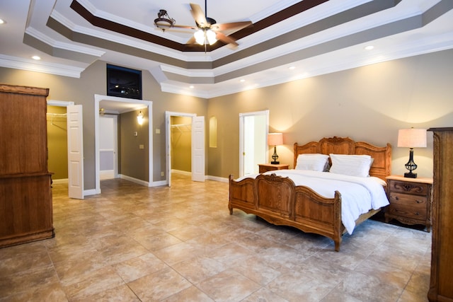 bedroom with a spacious closet, ceiling fan, a raised ceiling, and ornamental molding