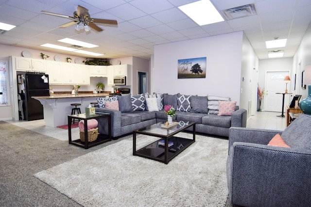 living room featuring a paneled ceiling, ceiling fan, and light colored carpet