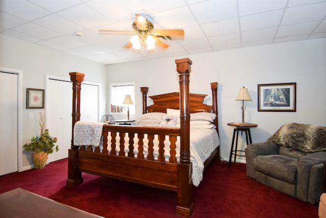 bedroom featuring a paneled ceiling, dark carpet, and ceiling fan