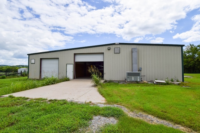 view of outbuilding featuring central AC unit, a garage, and a lawn