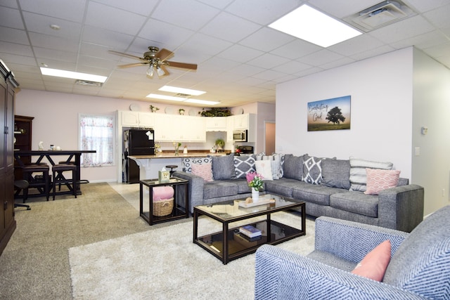 carpeted living room featuring ceiling fan and a paneled ceiling