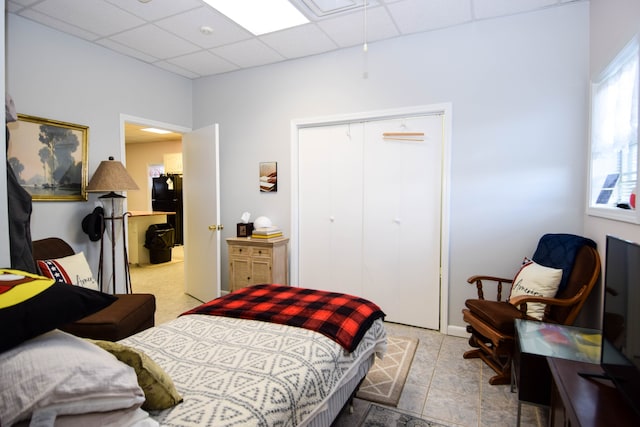 tiled bedroom featuring a closet and a paneled ceiling