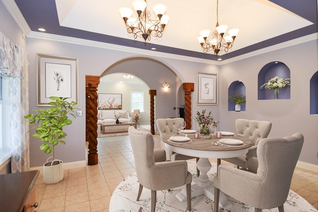 dining area featuring an inviting chandelier, ornamental molding, baseboards, a tray ceiling, and arched walkways
