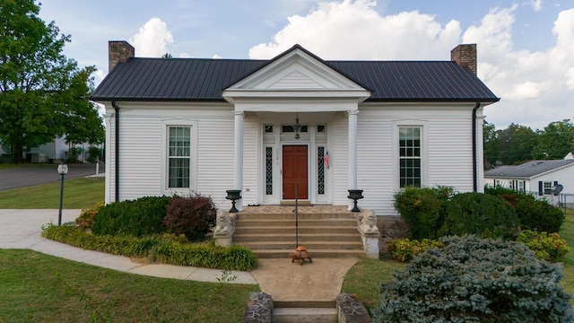 view of front of house featuring metal roof and a chimney
