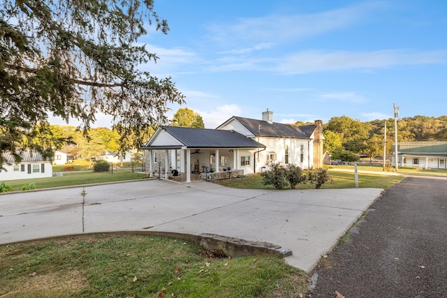 bungalow-style house with curved driveway, ceiling fan, a front lawn, and metal roof