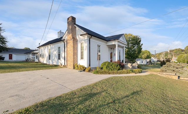 view of side of property featuring a chimney and a lawn