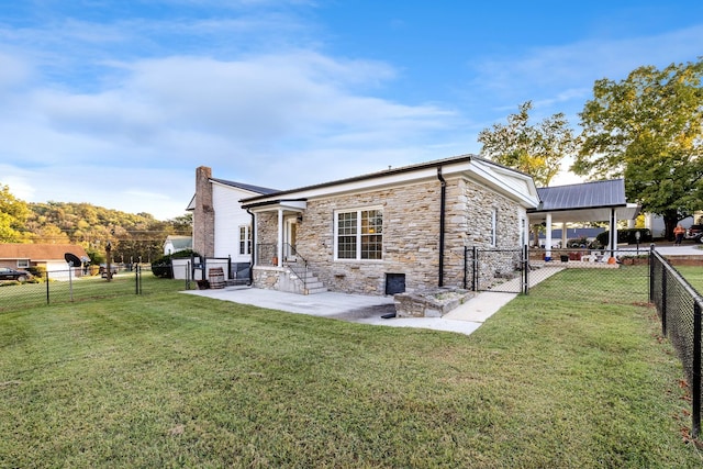 back of house featuring a lawn, a fenced backyard, stone siding, and a gate