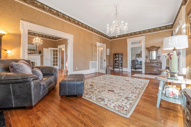 living room with visible vents, an inviting chandelier, ornamental molding, and wood finished floors
