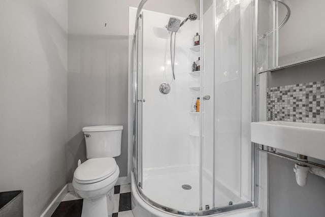 full bath featuring toilet, decorative backsplash, a stall shower, and baseboards