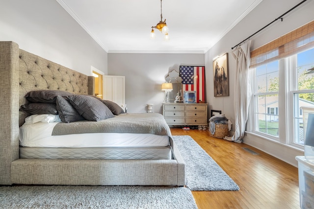 bedroom featuring visible vents, ornamental molding, and wood finished floors