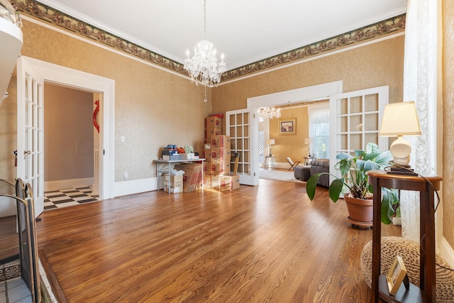interior space with ornamental molding, french doors, a notable chandelier, and wood finished floors